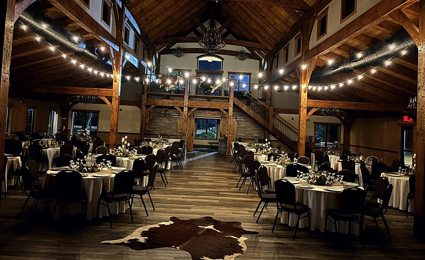 The hall strung with bistro lights between the timber posts, round tables set on the wood floor
