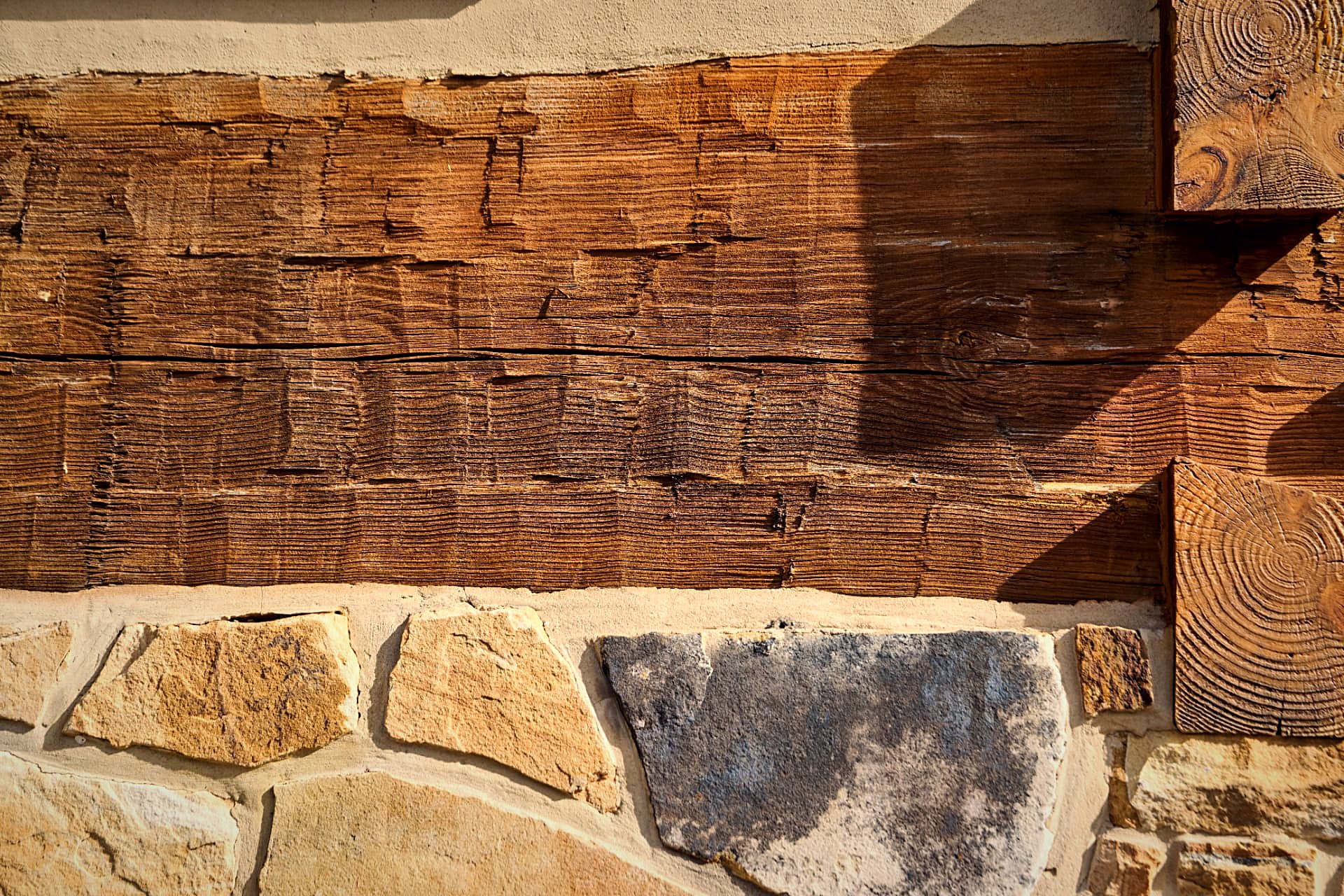 Hewn log texture, white chinking, and the stone foundation below