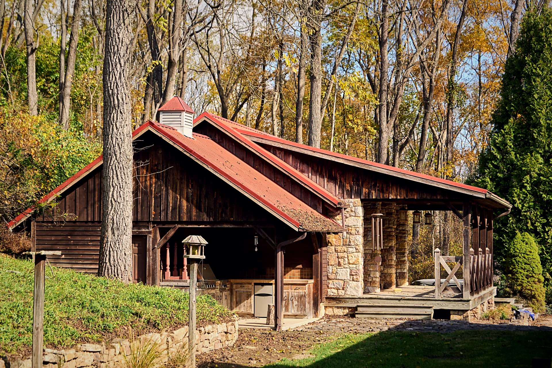 The timber-frame summer kitchen and pavilion under an ember-red standing-seam roof with cupola