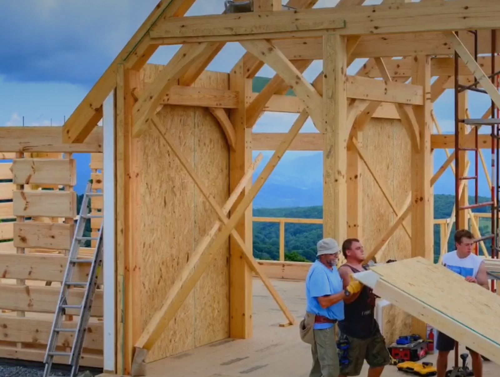 Hearthstone crew setting a wall panel inside a raised timber frame