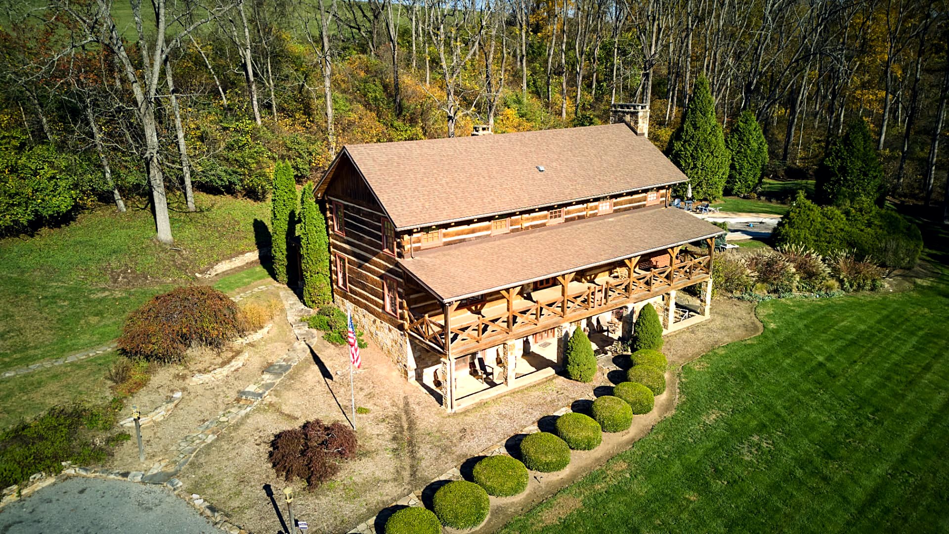 Aerial over the log home's roofline and wraparound porch