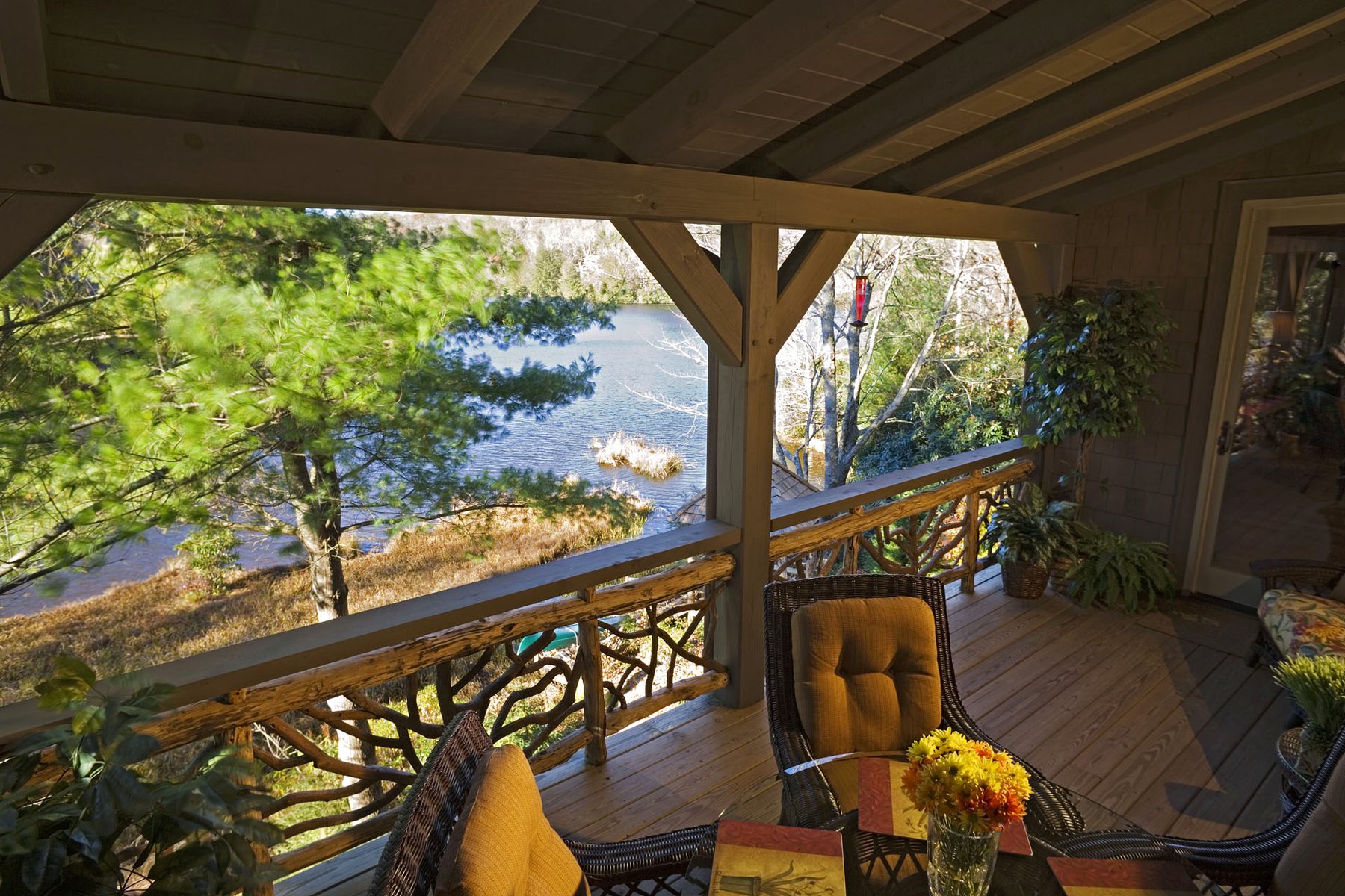 Covered porch with mountain-laurel railings looking out over the lake through timber posts