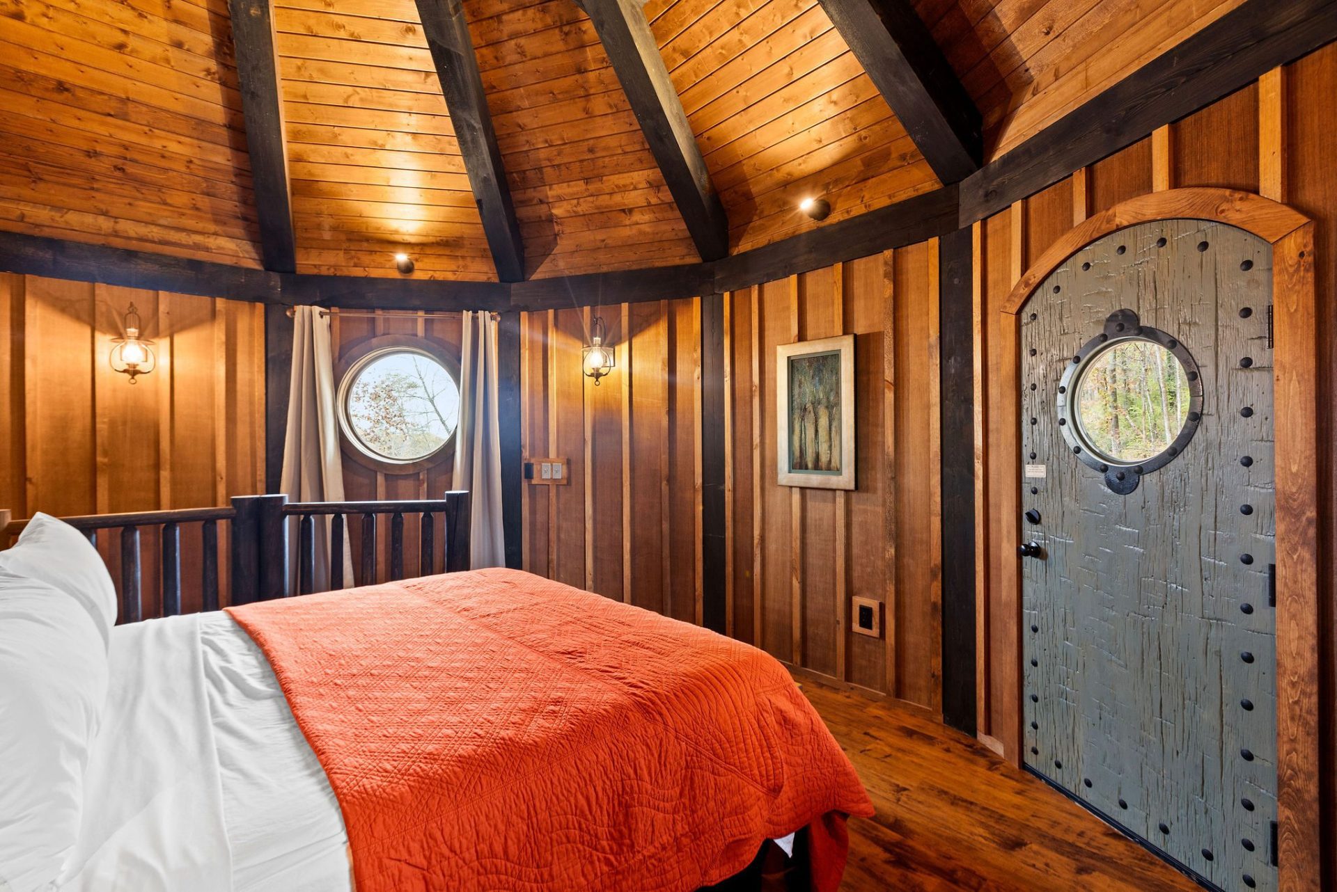 Elven Treehouse king bed beneath the radial rafter ceiling with round window and arched door
