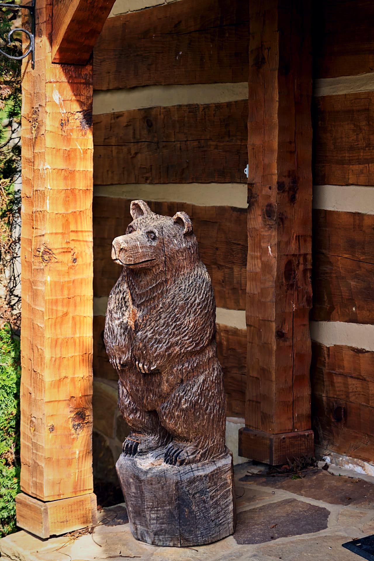 Carved black bear standing watch beside the timber entry posts