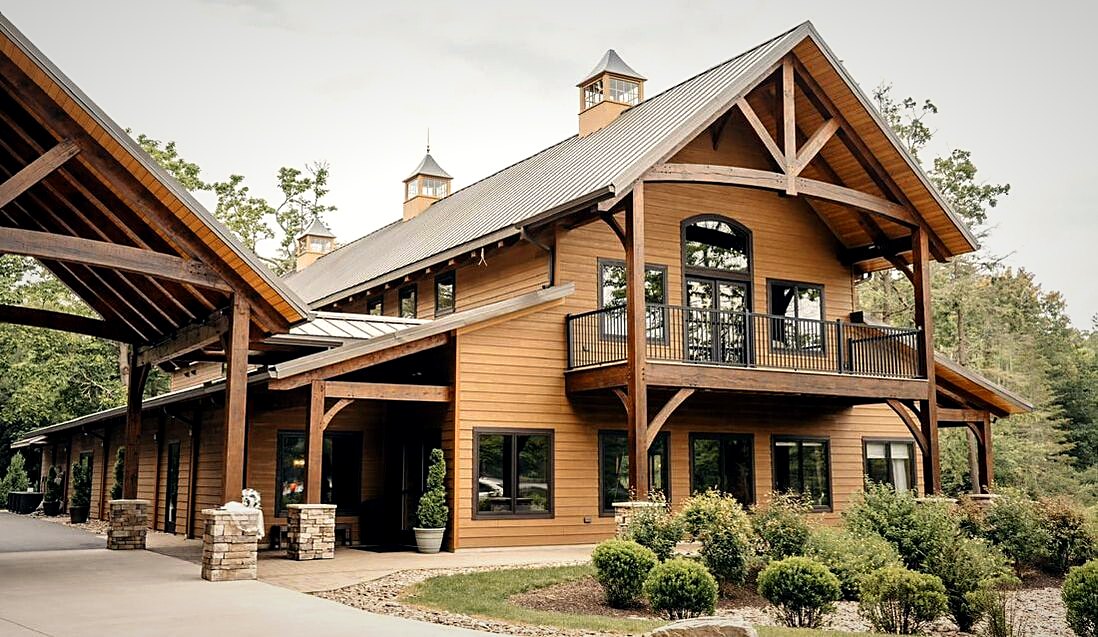 The timber porte-cochere and entry gable seen from the drive on a summer afternoon