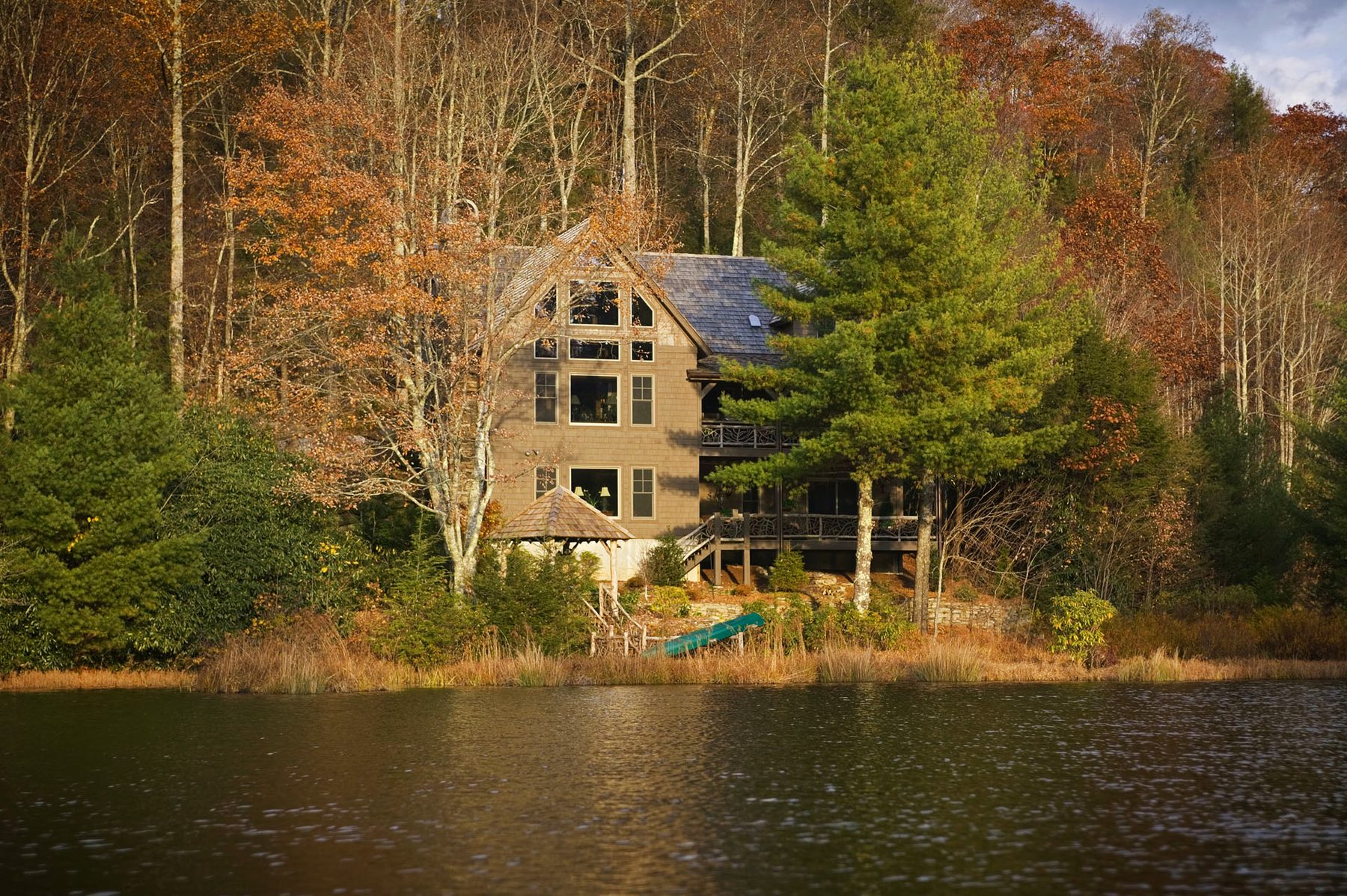 Autumn lakefront elevation of the Parmalee Timber Frame framed by hardwoods in full color