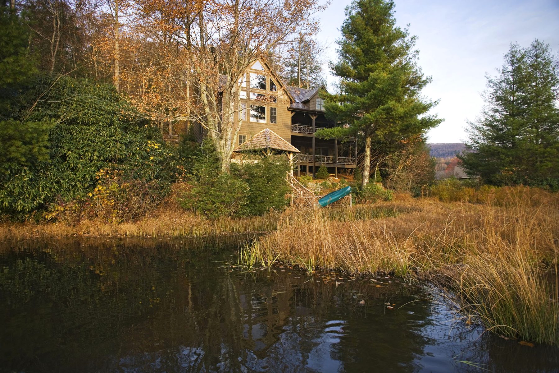 Late-day reflection of the timber frame across still lake water and marsh grass