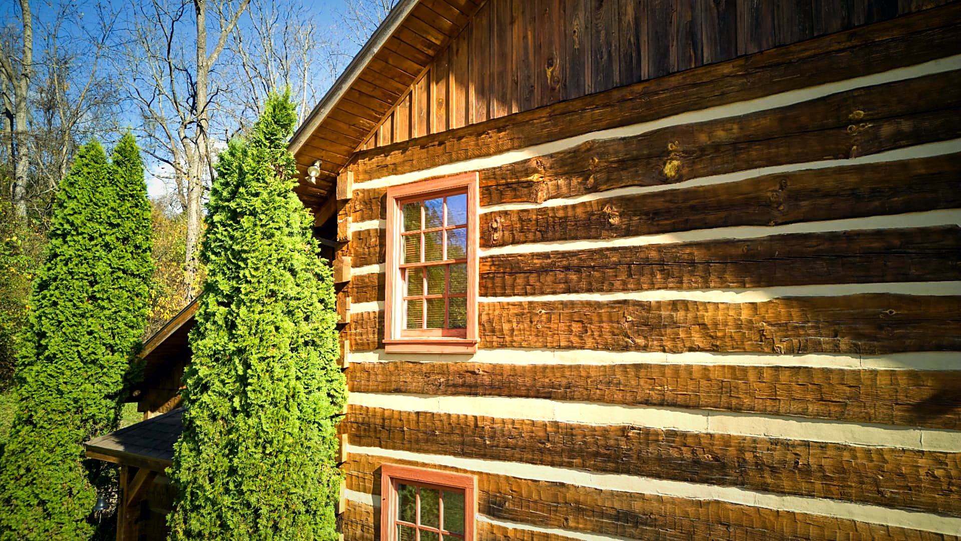 Hewn logs, chinking, and an ember-red window frame in close view