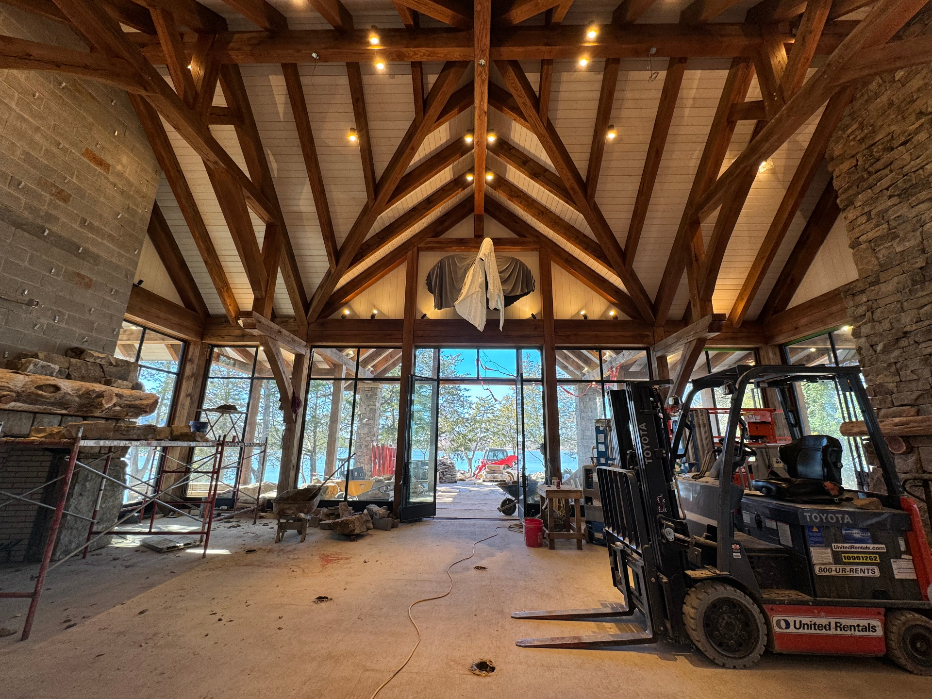 Pangle Point great room during raising — hammer-beam trusses over stone hearths