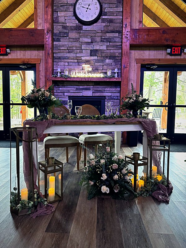 Stone fireplace wall inside the hall with a timber mantel and flanking glass doors to the patio