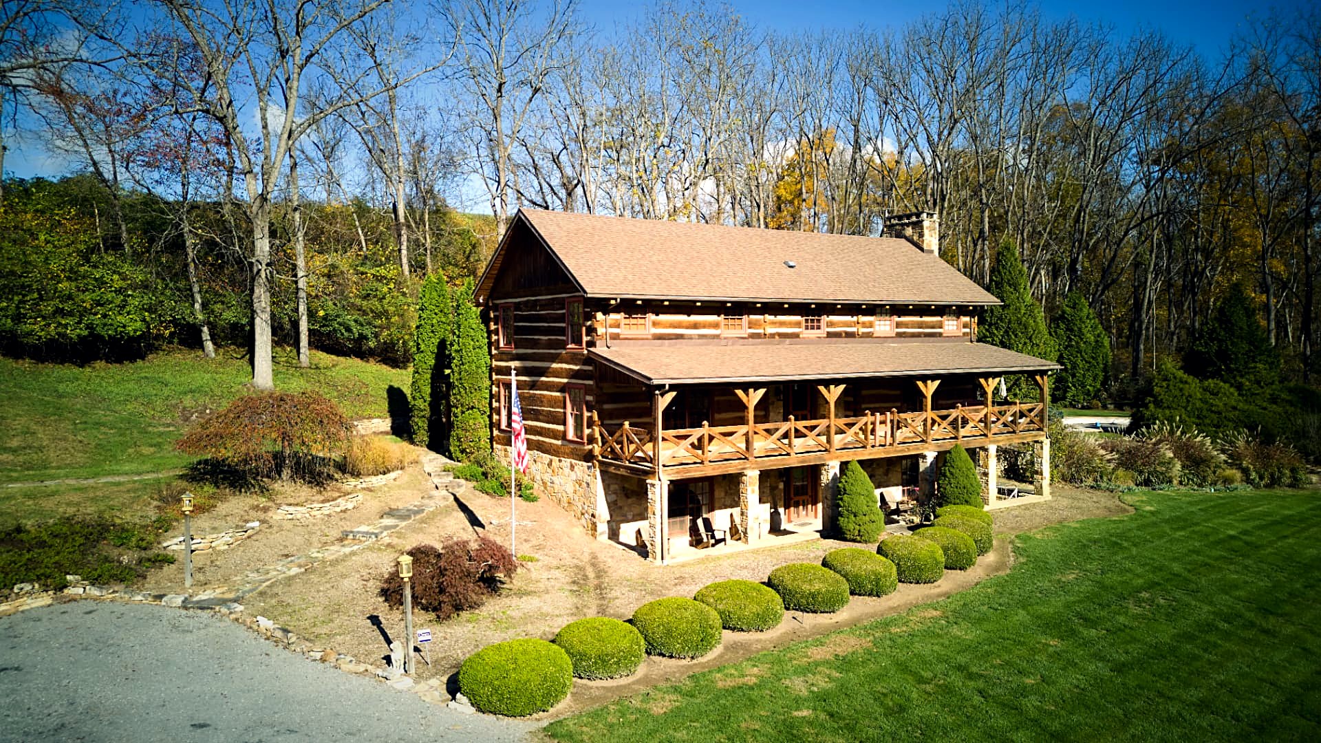 Three-quarter aerial of the log home with the flag in the foreground