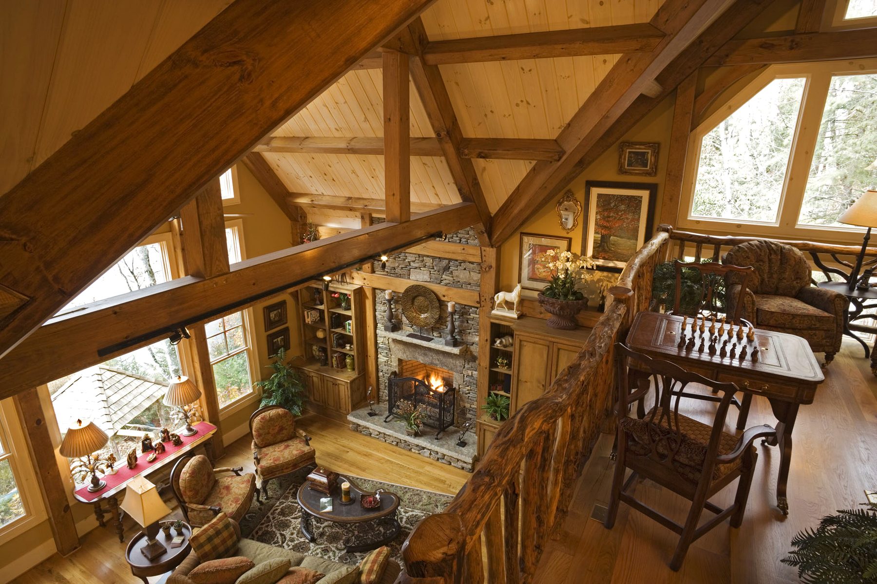 Great room seen from the loft — queen-post truss, wall of glass, and the lake beyond