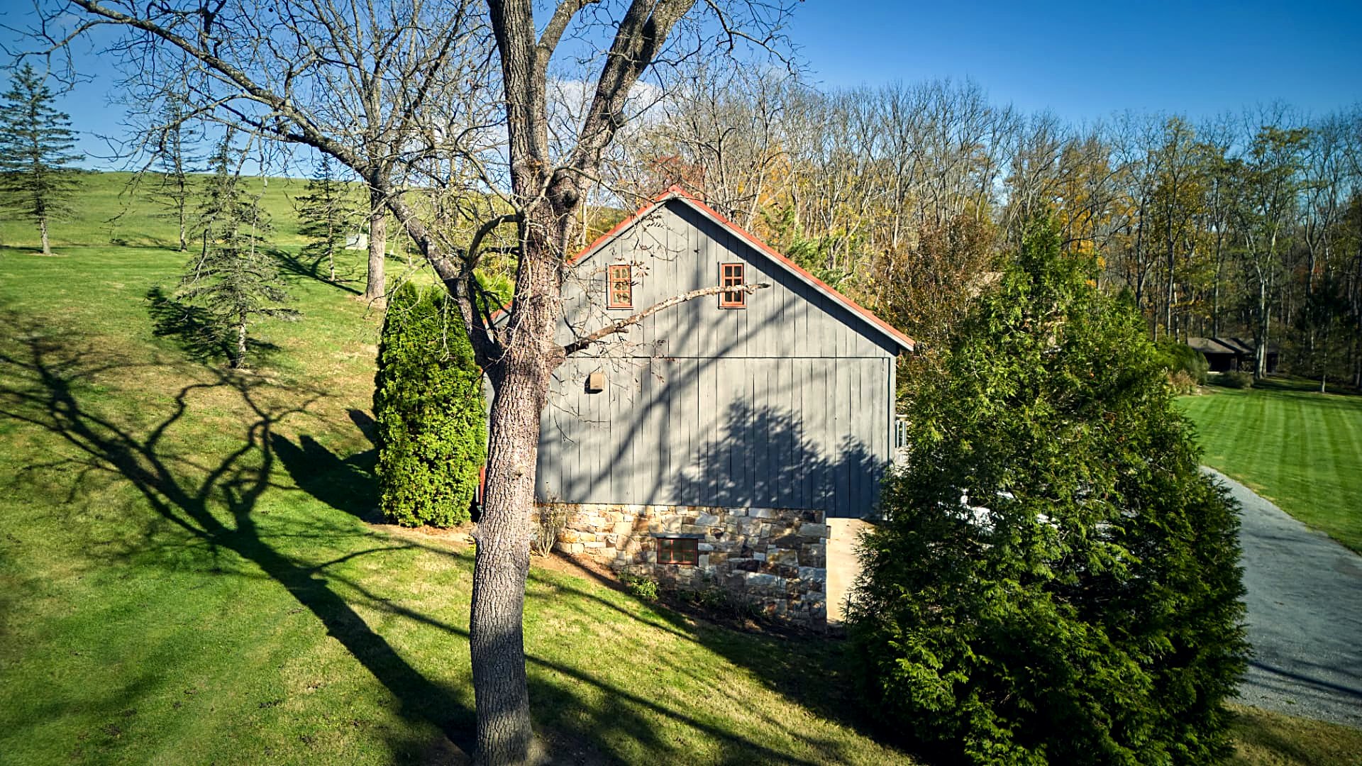 The timber-frame barn under its ember-red roof, set into the hillside