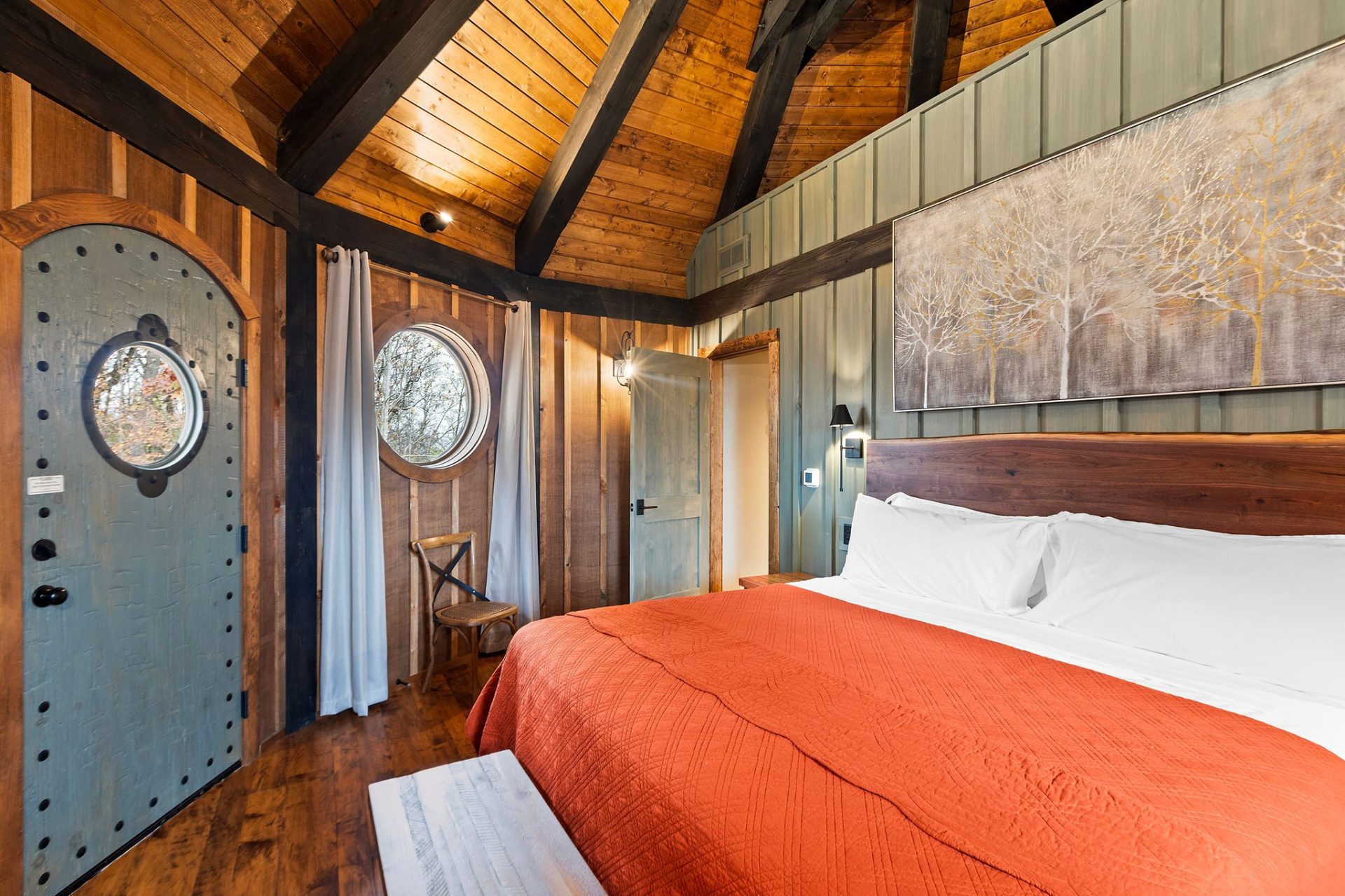Elven Treehouse bedroom looking toward the arched entry door under exposed timber rafters