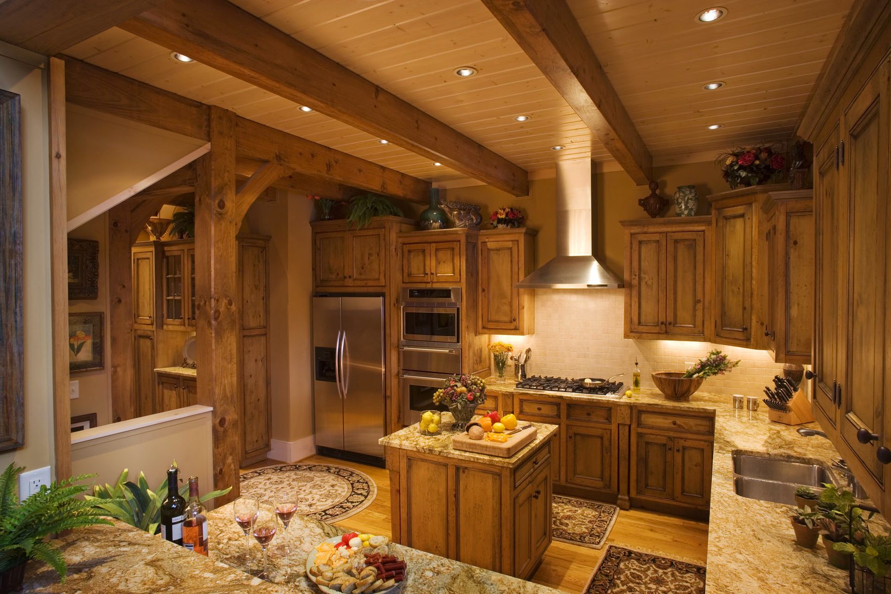 Kitchen with knotty-alder cabinetry by Ben Welch, timber posts, and a stone island beneath the beams