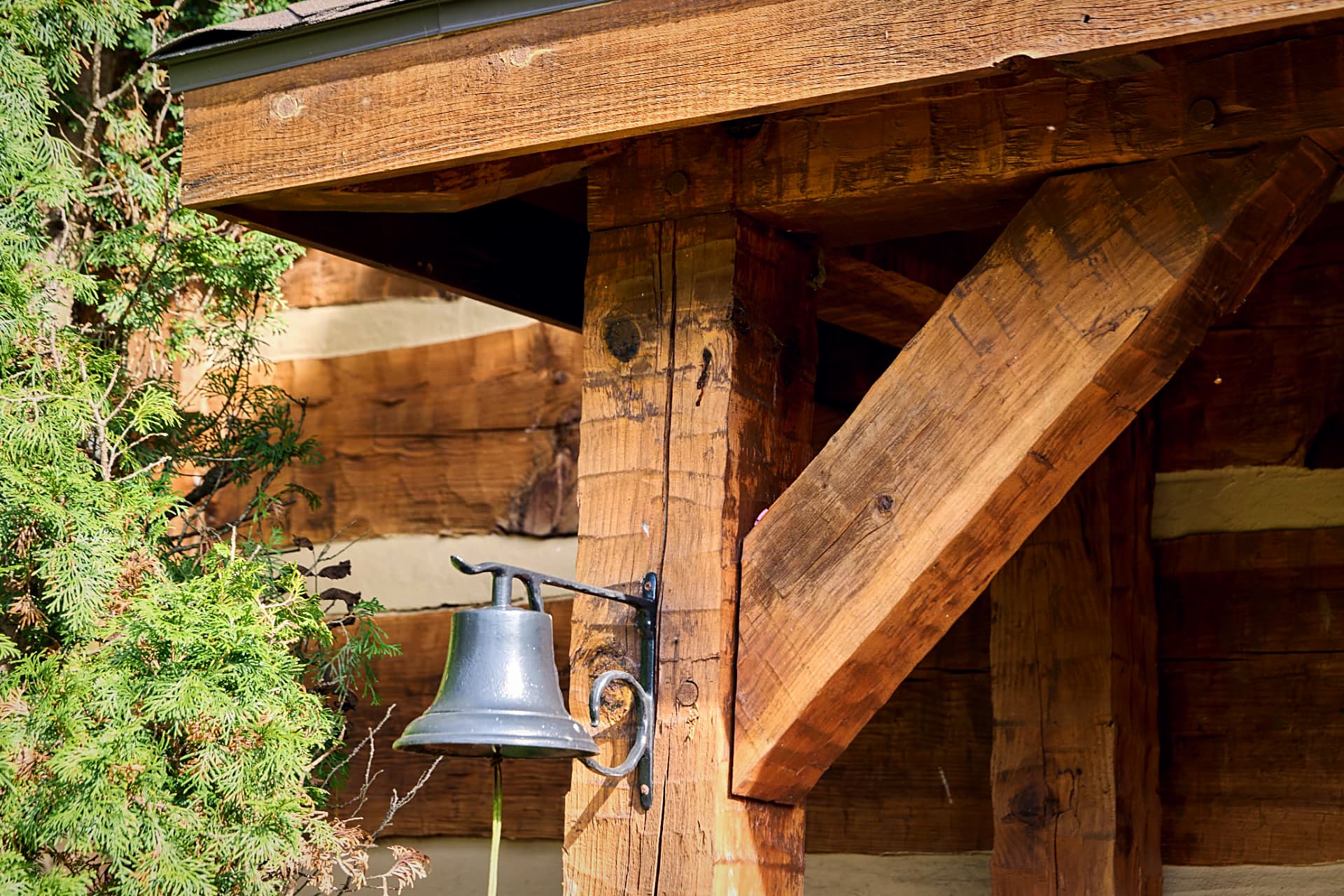 Cast-iron bell hung from a timber knee brace at the entry