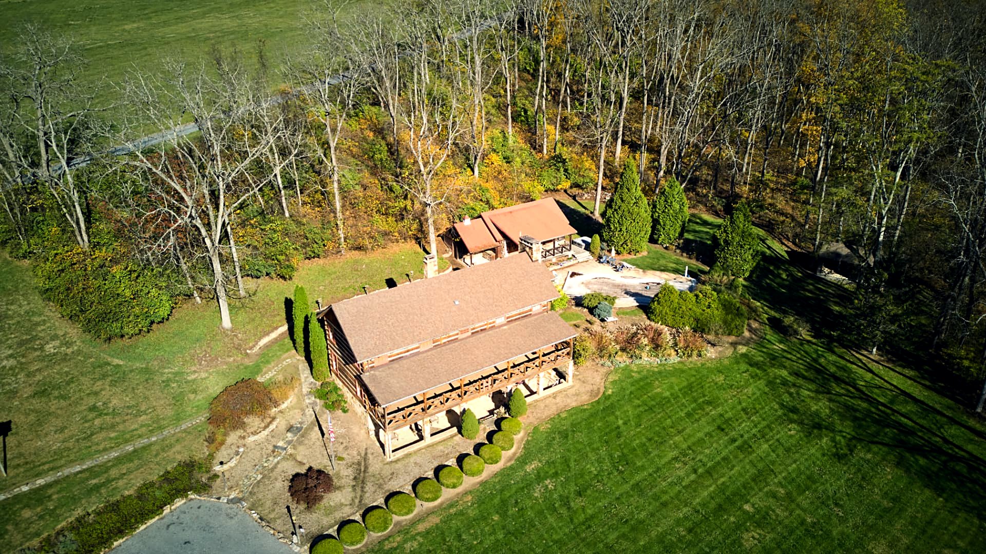 Low aerial along the log facade and clipped boxwood line