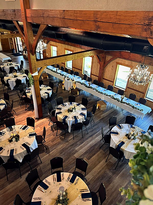 Interior of the timber hall showing the truss line, clerestory windows, and round tables set for dinner